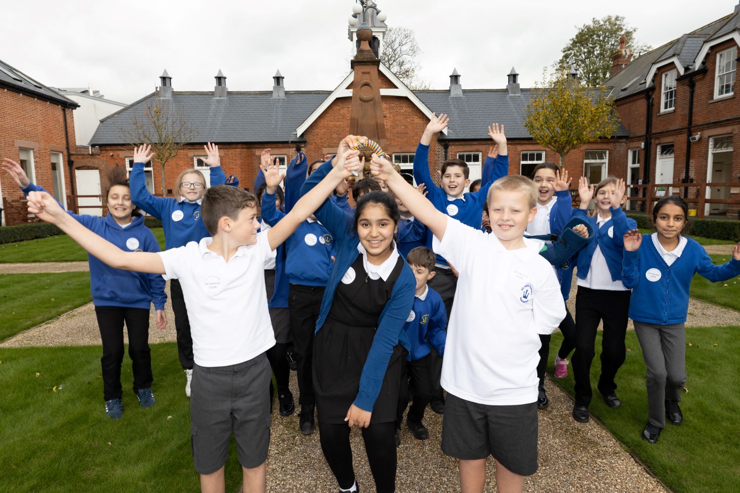 A group of primary school pupils in the courtyard of the National Horseracing Museum. The children at the front together hold a set of keys.