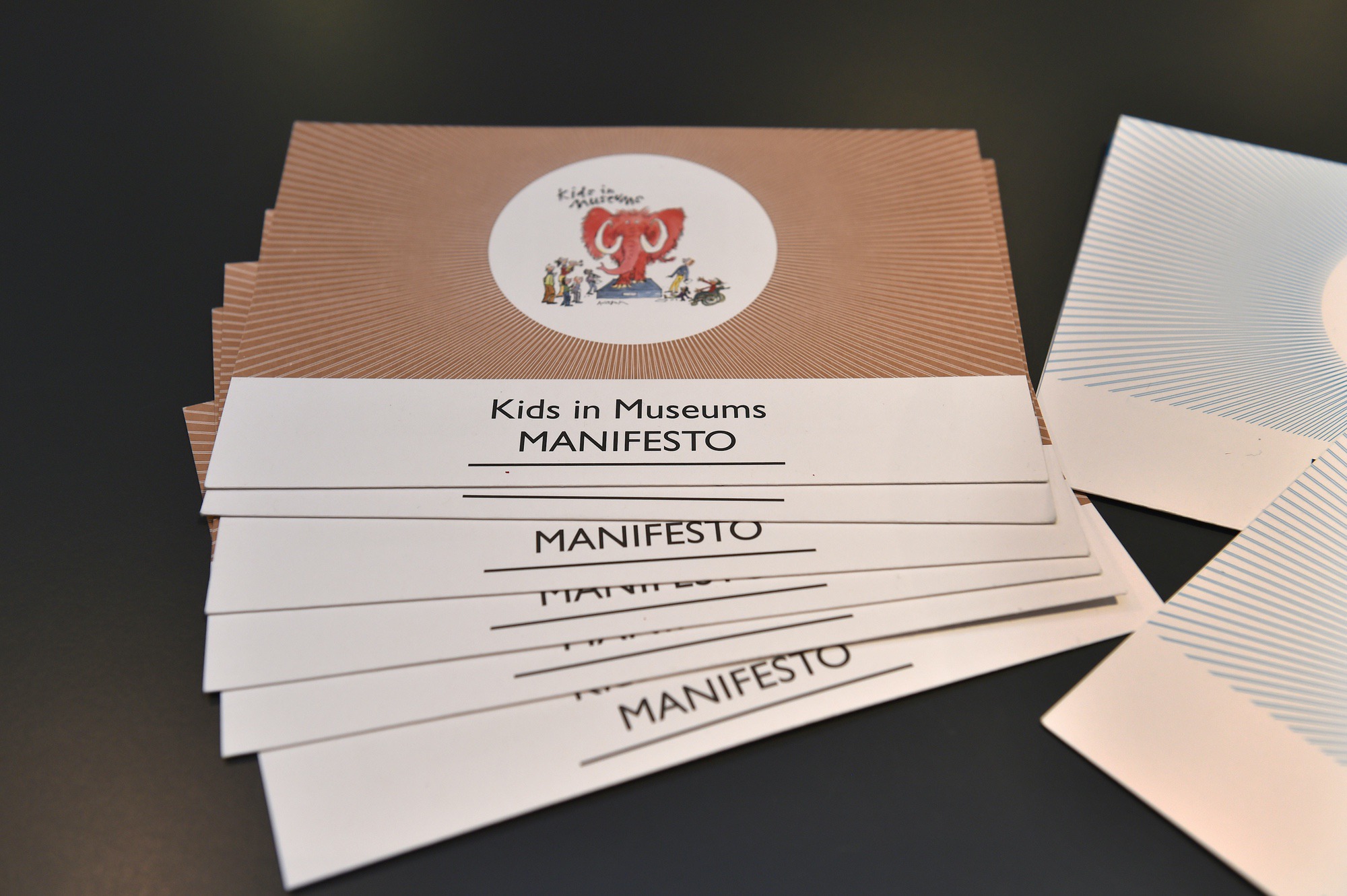 A pile of paper copies of the Kids in Museums Manifesto lying on a table.