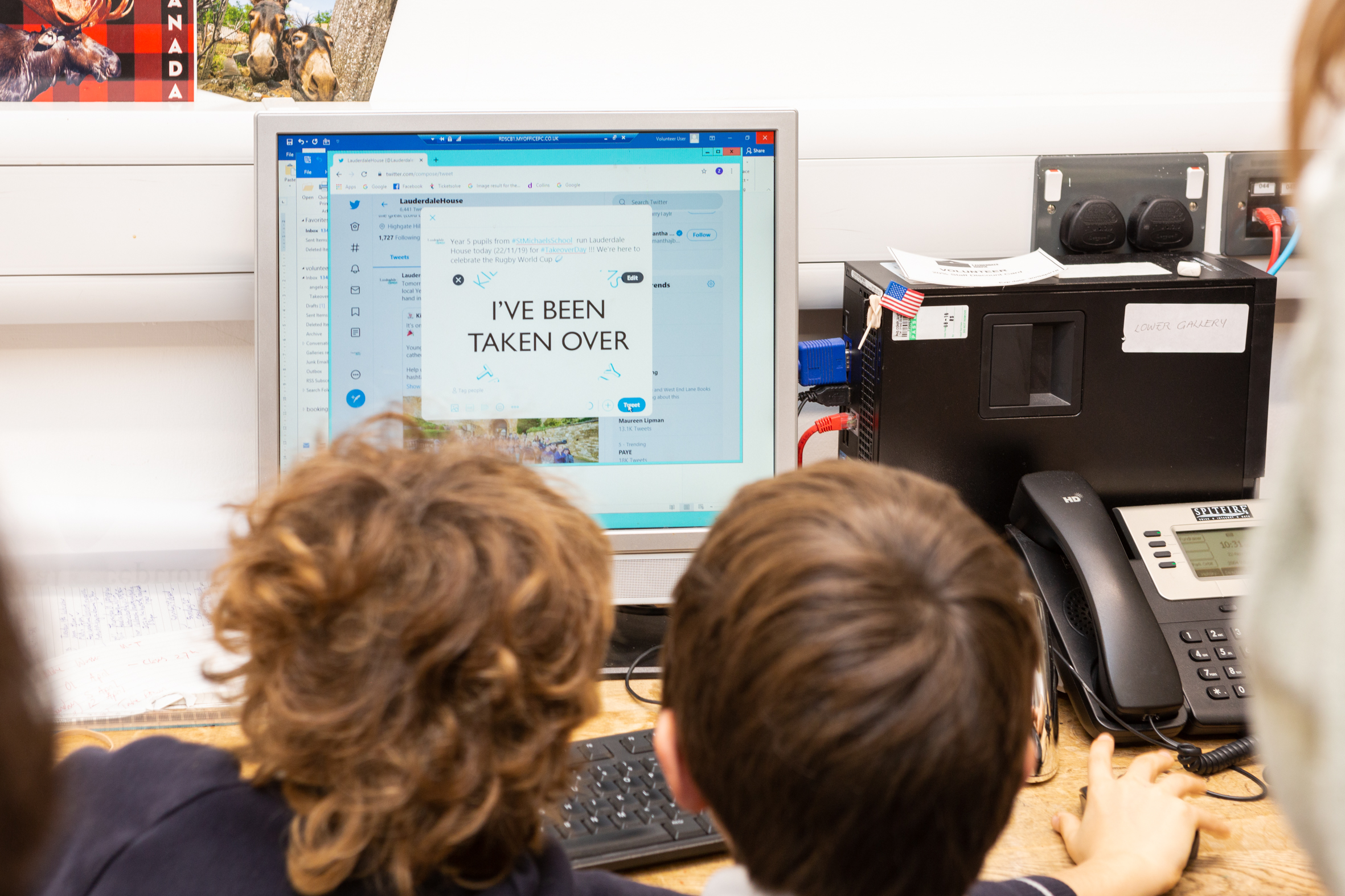 Two boys sitting facing towards a computer monitor where they are sending a tweet reading 'I've been taken over'' during the Lauderdale house Takeover Day.