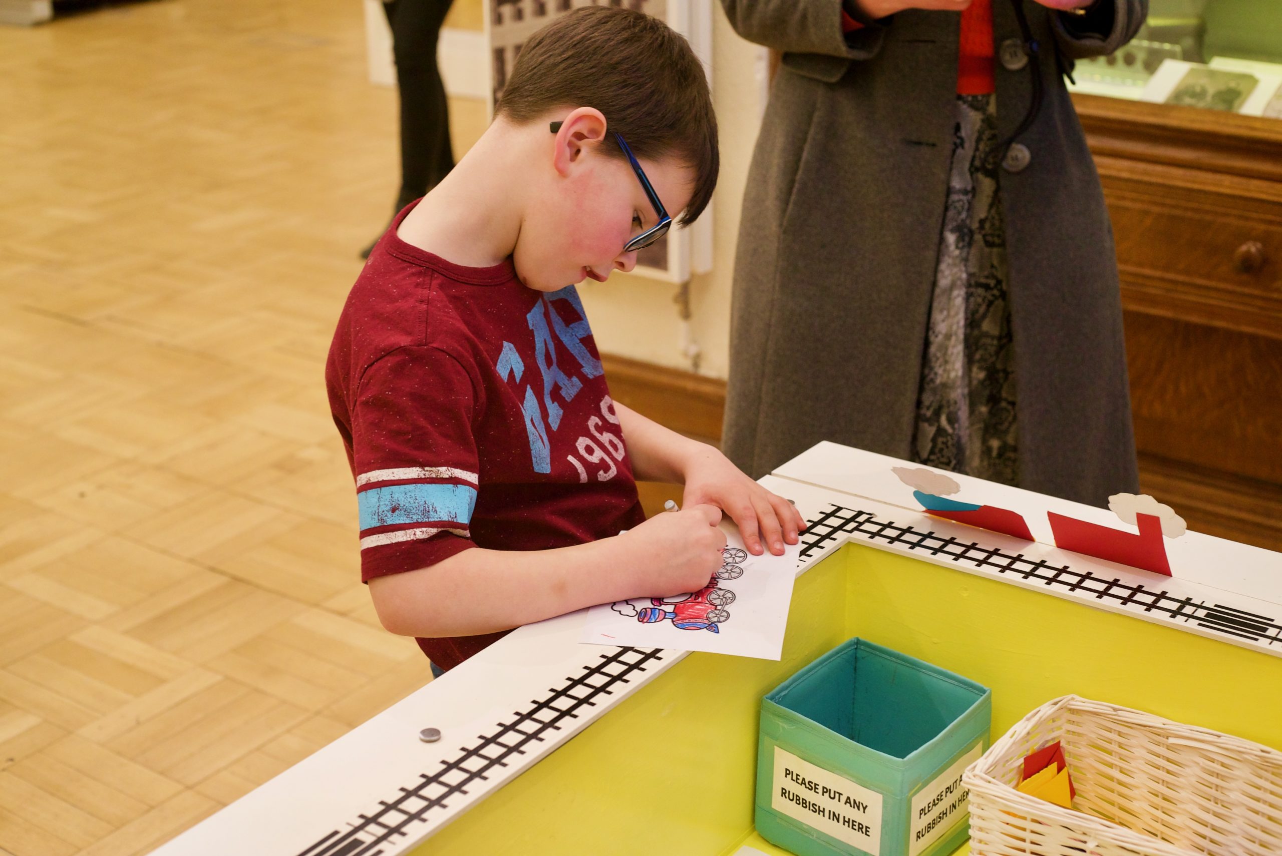 A young boy colouring next to an activity station at the Andrew Carnegie Birthplace Museum.