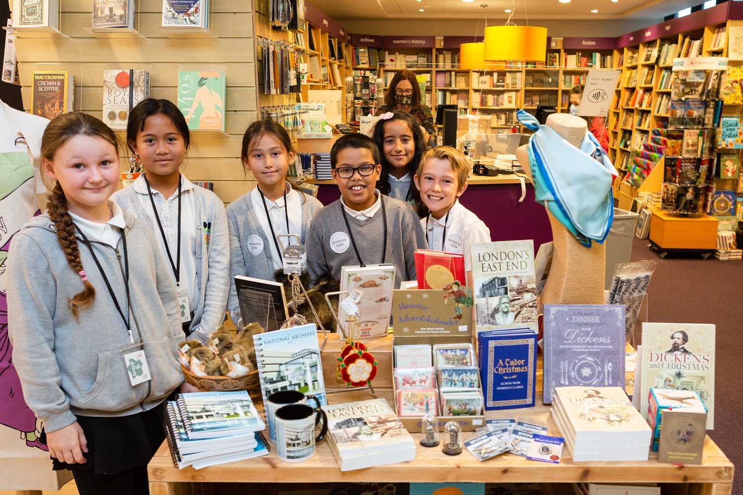 A group of six primary pupils gather around an island in the National Archives shop.