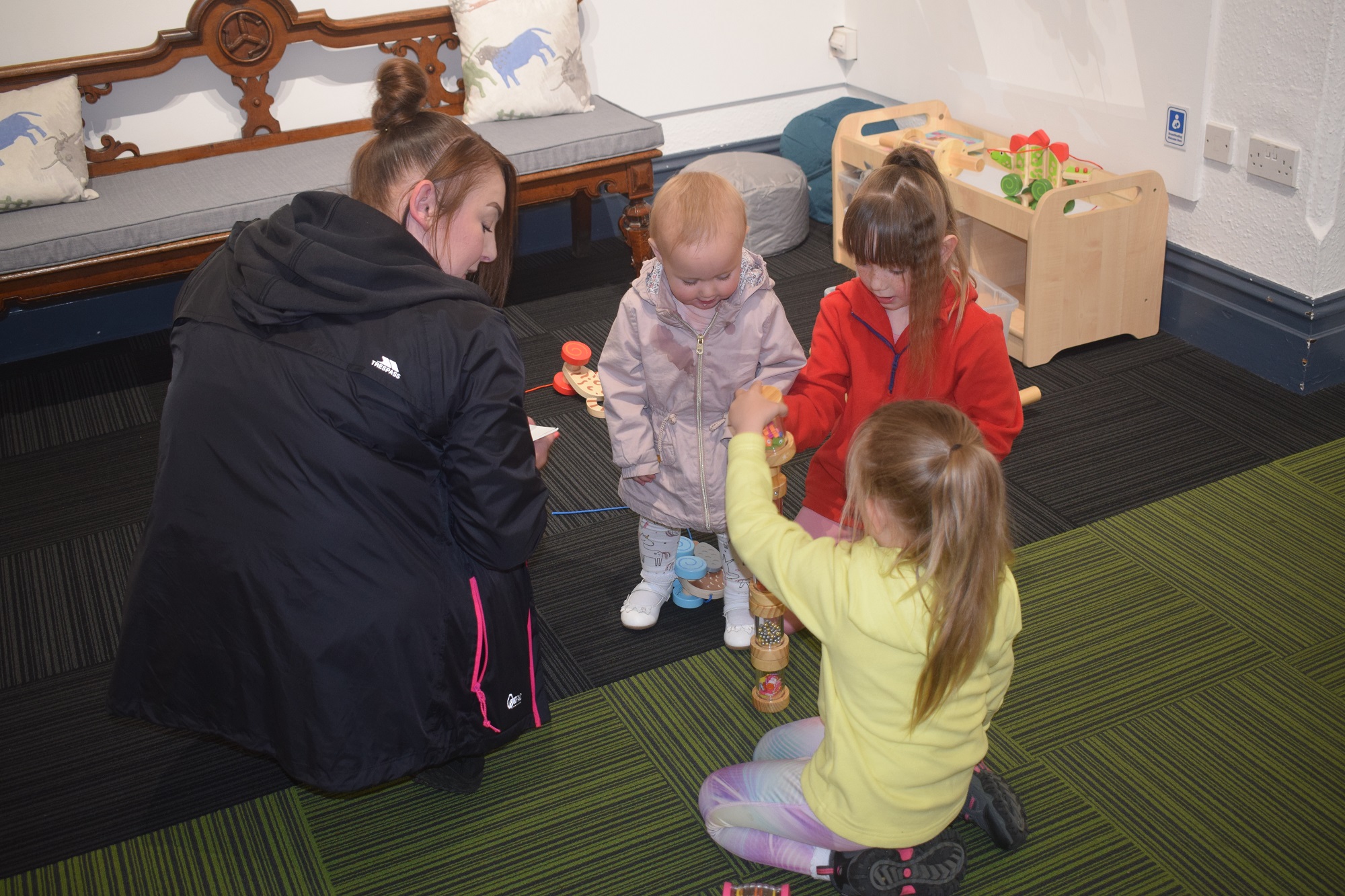 A mother and three small children play with toys in a cosy corner of the museum.