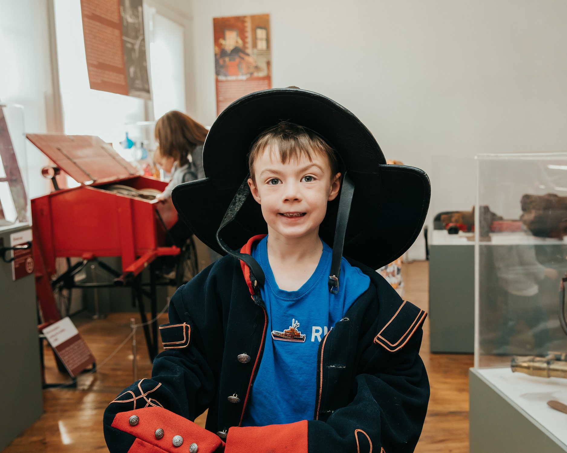 A young boy dressed up in historic fire fighter's uniform in a gallery in the National Emergency Services Museum.
