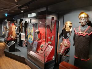 A museum display of roman armour, helmets, and shields.